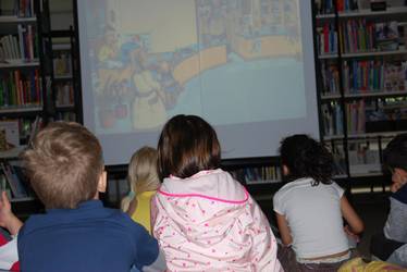 KInder sitzen vor einer Leinwand in der Bücherei