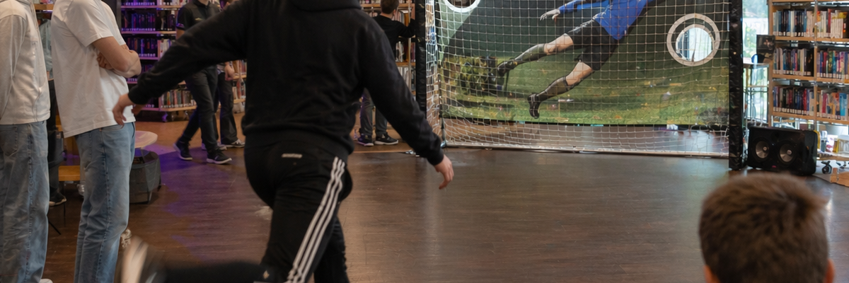 Ein Jugendlicher schießt einen Fußball auf eine Torwand