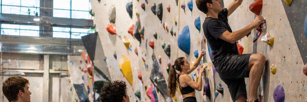 Zwei Jugendliche klettern an einer Kletterwand