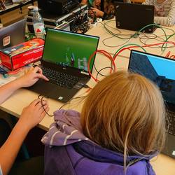 Kinder sitzen an Laptops und bauen Welten in Minecraft