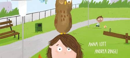 Ein Kind steht mit einer Eule auf dem Kopf und weiteren Tieren an ihrem Körper im Park