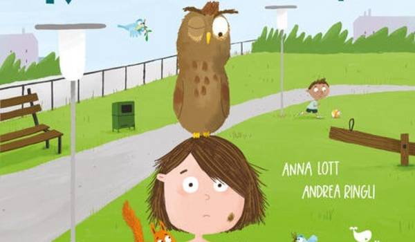 Ein Kind steht mit einer Eule auf dem Kopf und weiteren Tieren an ihrem Körper im Park